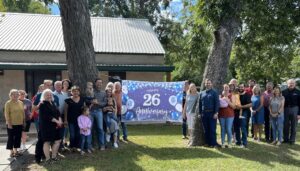 WEI Staff, Family, and Friends gathered together around our banner outside our new office celebrating 26 years of service to our communities.